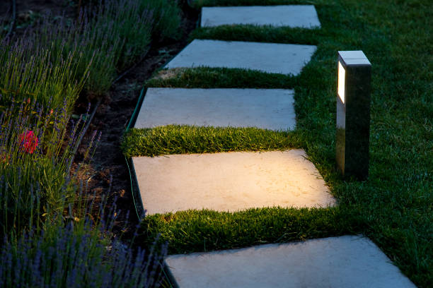 istock square tile marble path illuminated by a lantern in the backyard, a winding path in the flowerbed garden and lawn in the evening. 1157221569