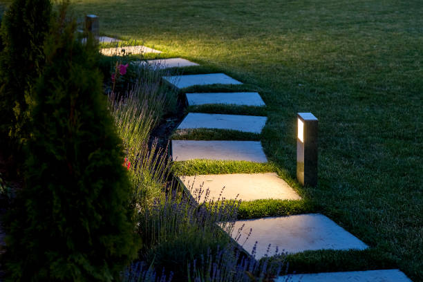 istock marble path of square tiles illuminated by a lantern glowing with a warm light in a backyard garden with a flower bed and a lawn copy space. 1157221601