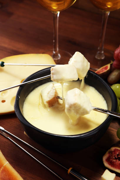 istock Gourmet Swiss fondue dinner on a winter evening with assorted cheeses on a board alongside a heated pot of cheese fondue 1157224088
