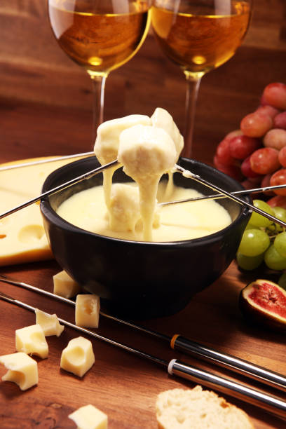 istock Gourmet Swiss fondue dinner on a winter evening with assorted cheeses on a board alongside a heated pot of cheese fondue 1157224120