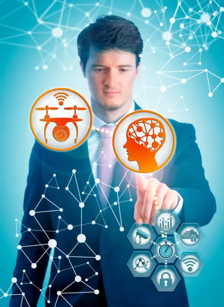 Concentrated young IT manager pairing artificial intelligence and smart drone for real-time data processing in surveillance tasks. Tech concept for AI, UAV, security monitoring, machine learning.