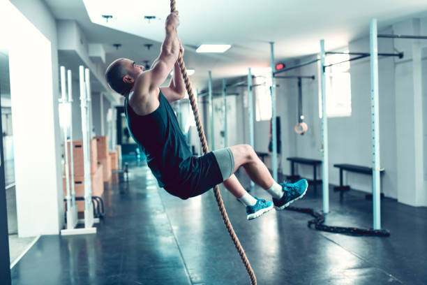 istock Male Athlete Doing Rope Climbing Exercises In Gym 1157236884