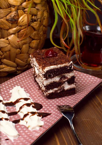 Sliced Tiramisu cake made of chocolate and white sponge. A piece of dessert on wooden boards. - Image