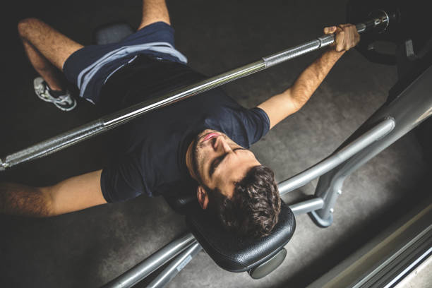 młody człowiek robi ćwiczenie wyciskania na ławce - gym weight bench exercising weights zdjęcia i obrazy z banku zdjęć