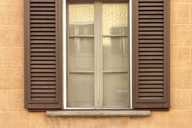 istock brown wooden window with shutters on yellow textural wall 1157246950