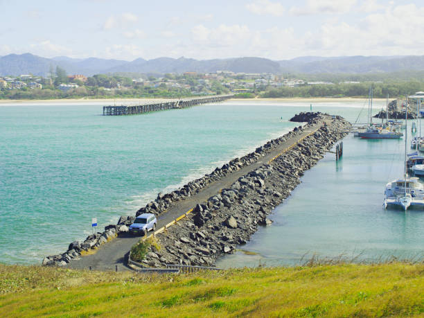 Coffs Harbour Marina rock breakwall and ocean timber jetty. Coffs Harbour Marina rock breakwall and the nearby restored Coffs Harbour ocean timber jetty. Safe haven for sailing and cruising vessels. New South Wales, Australia. downunder stock pictures, royalty-free photos & images