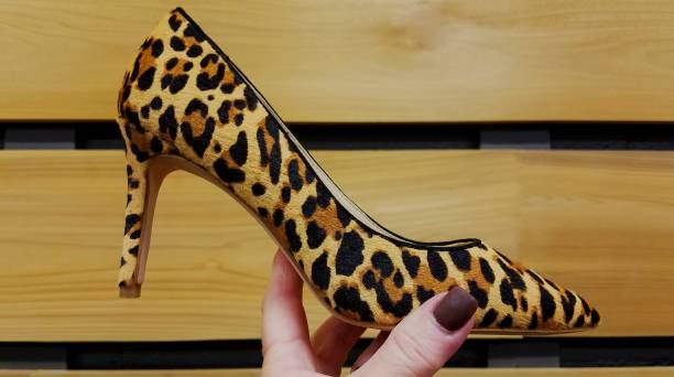 istock Single Leopard Stiletto Heel Shoe, Held Up to a Wood Plank Background 1157257869