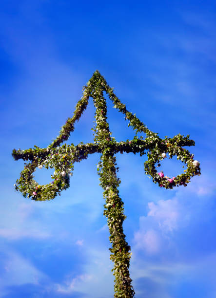 Maypole made of green leaf and the blue sky and some white clouds behind