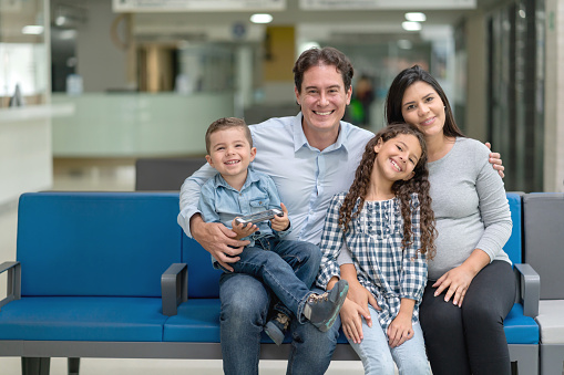 Portrait of a Latin American family looking very happy at the hospital and smiling in the waiting room