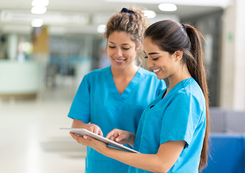 Portrait of two happy female doctors working at a hospital using a tablet computer â healthcare and medicine concepts