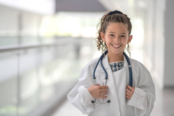 Happy girl playing to be a doctor at a hospital Happy girl playing to be a doctor at a hospital wearing a lab coat and looking at the camera smiling â healthcare and medicine concepts career girl stock pictures, royalty-free photos & images
