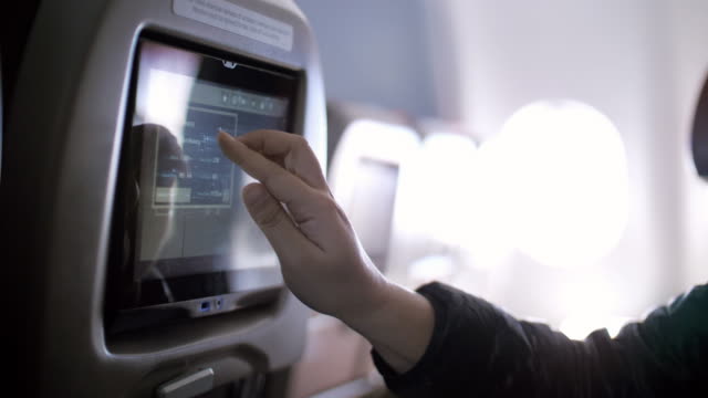 Inside the airplane with Woman passenger using Multimedia touch screen on cabin of airplane , SLOW MOTION