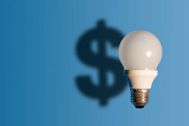 istock Light bulb on bright blue background with a dollar sign shadow. Conception good idea it's money. 1157268351