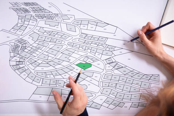istock Human Hand Holding Pencil Over Cadastre Map 1157269238