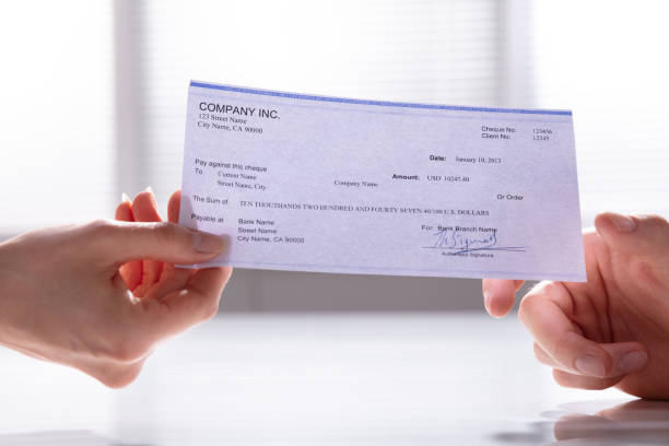 istock Woman's Hand Giving Cheque To Man 1157269239