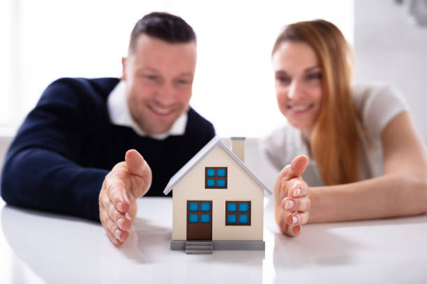 istock Male And Female Hands Protecting House Model 1157269295