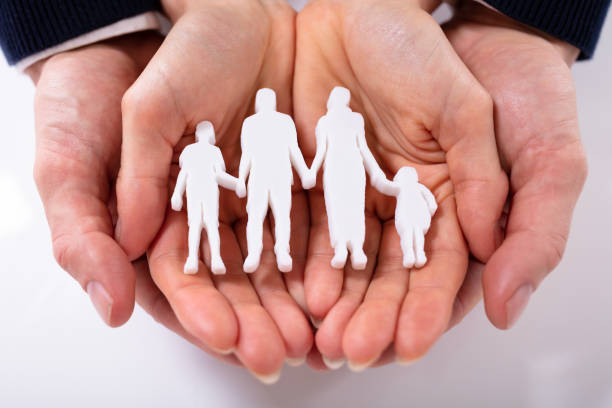 Couple's Hand With Family Figure Over White Surface