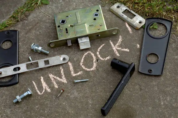 outdoor close-up of the disassembled door lock and a word Unlock written on asphalt
