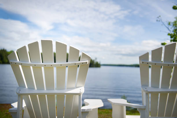 istock White Muskoka chairs on a dock overlooking a lake 1157270378