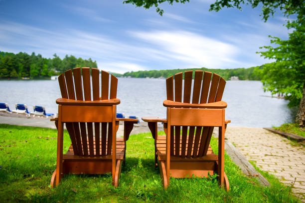 istock Adirondack chairs on green grass overlooking a lake 1157270390