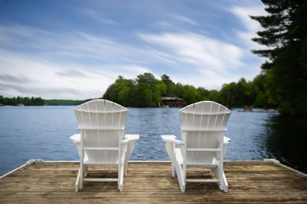istock White Muskoka chairs on a dock overlooking a lake 1157270429