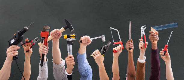 Close-up Of People's Hand Holding Carpentry Tools Against Black Background