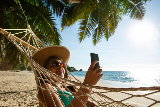 istock Smiling Woman Using Mobile Phone On Beach 1157270938
