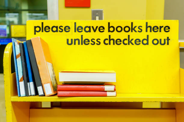 yellow library book cart with sign in black letters, and books stacked on a shelf to be put away. - library book shelf generic imagens e fotografias de stock