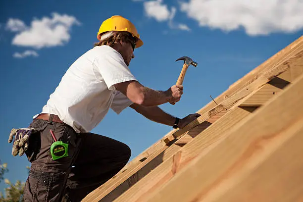 worker on a roof with hammer