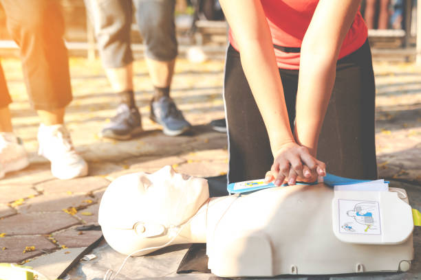 Asian female or runner woman training CPR demonstrating class in park by put hands and interlock finger over CPR doll give chest compression. First aid training for heart attack people or lifesaver. mujer asiática o mujer corredora que entrena rcp demostrando clase en el parque poniendo las manos y enclavando el dedo sobre la muñeca decpr dar compresión del pecho. entrenamiento de primeros auxilios para personas de infarto o salvavidas.
