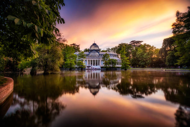 sunset at crystal palace, parque del Buen Retiro park. Madrid, Spain 05 june 2019 - Madrid, Spain: Tourists and locals gather outside the Crystal Palace (Palacio de Cristal) in the Retiro Park in Madrid at sunset. Designed by architect Ricardo Velázquez Bosco, it was built in 1887 to exhibit flora and fauna from the Philippines. palacio de cristal photos stock pictures, royalty-free photos & images