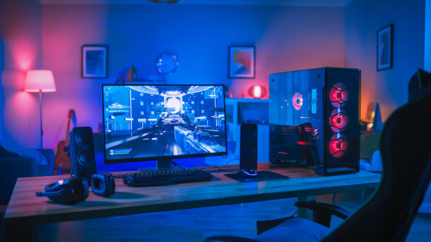 puissant jeu d'ordinateur personnel rig avec jeu de tir à la première personne à l'écran. monitor stands on the table at home. chambre confortable avec design moderne est lit avec rose néon light. - pièces dordinateur photos et images de collection