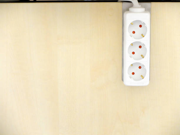 istock Electrical extension cord with three electrical power outlets mounted on the wooden surface. 1157291324