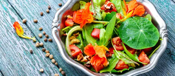 Healthy salad with flowers, nasturtium leaves, tomatoes and nuts. Summer food.Indian salad.Capuchin