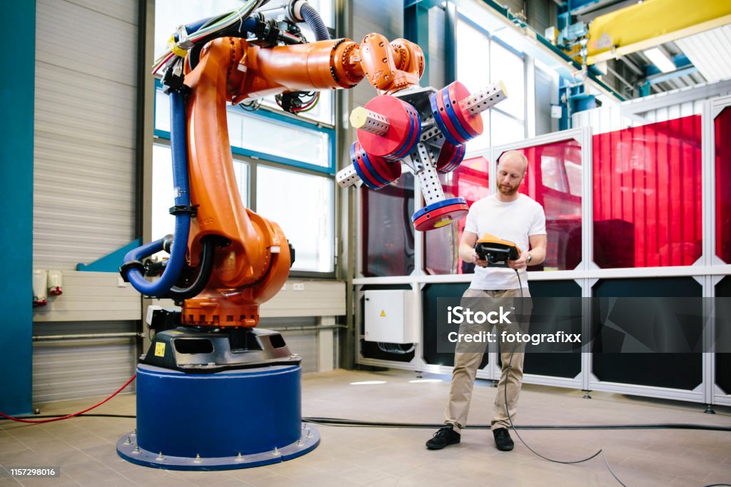 industry 4.0: Young engineer works at a robotic arm Robot Stock Photo
