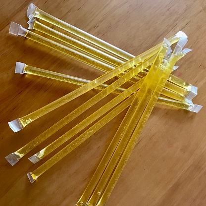 Yellow bee sticks lie beautifully on wooden kitchen table, tasty organic honey dessert. The photo consists of long bee sticks with taste of honey. Yummy golden sticks made by bees from natural honey.