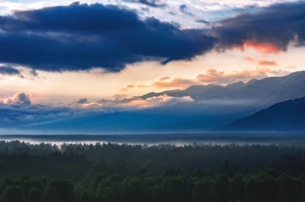 istock Dramatic Sunrise over Altai Mountains, Kazakhstan, With Thick Evergreen Forest in Foreground Covered with Fog. 1157303437