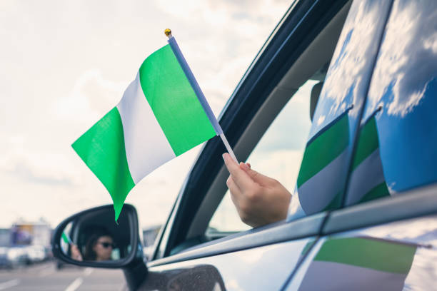 mujer o chica sosteniendo la bandera de nigeria desde la ventana abierta del coche - women open traditional culture human hand fotografías e imágenes de stock