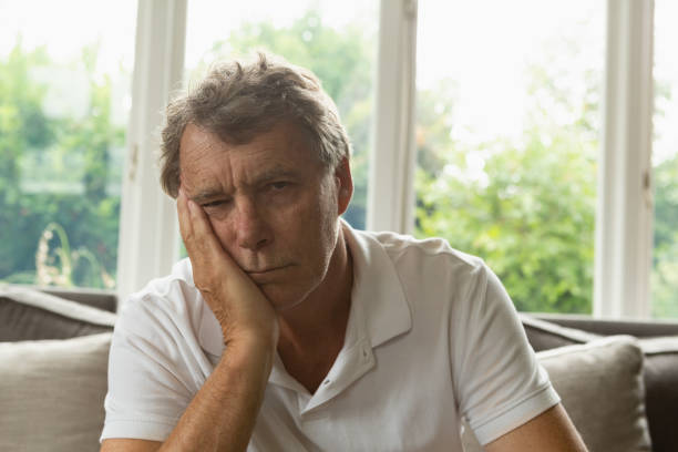 istock Active senior man with hand on face sitting on sofa in a comfortable home 1157311226