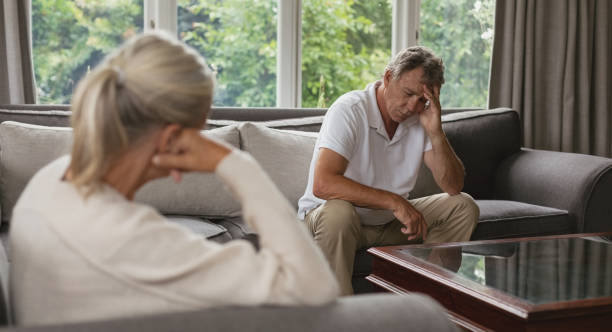 istock Active senior man with hand on forehead sitting on sofa in a comfortable home 1157312052