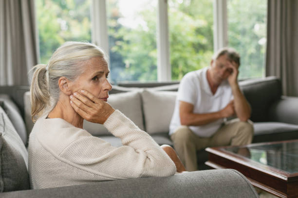 aktive seniorin mit hand auf dem gesicht sitzend auf dem sofa in einem komfortablen haus - couple senior adult sadness emotional stress stock-fotos und bilder