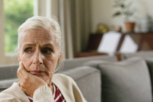istock Active senior woman with hand on face sitting on sofa in a comfortable home 1157312221