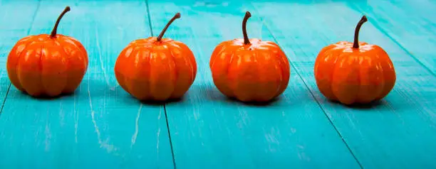 A Close Up of Several Small Pumpkins Lined up in a Row on Rustic Old Wooden Boards against Medium Brown Background with Copy Space