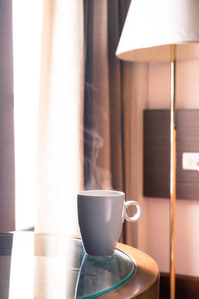 istock One cup hot coffee with smoke on the glass table in the window light in room. 1157314062