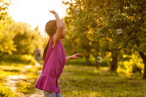 istock Cute little girl is blowing a soap bubbles 1157316427
