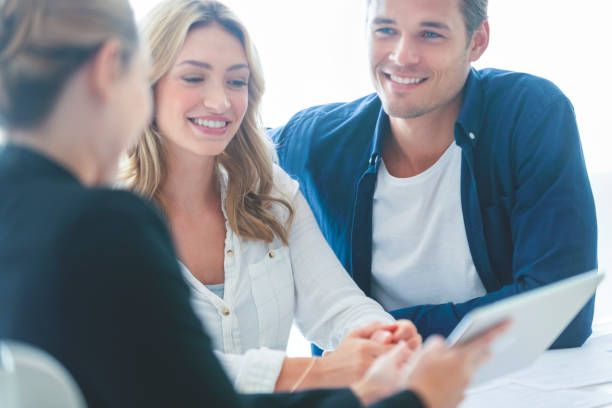 istock Real estate agent with couple looking through documents. 1157316733
