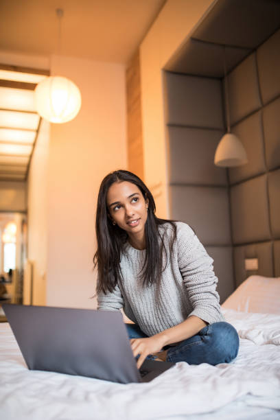 istock Young pretty woman using laptop on bed 1157316917