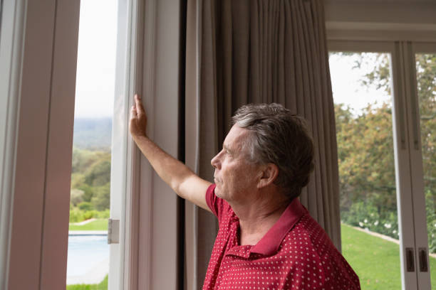 istock Active senior man looking through window in a comfortable home 1157317520