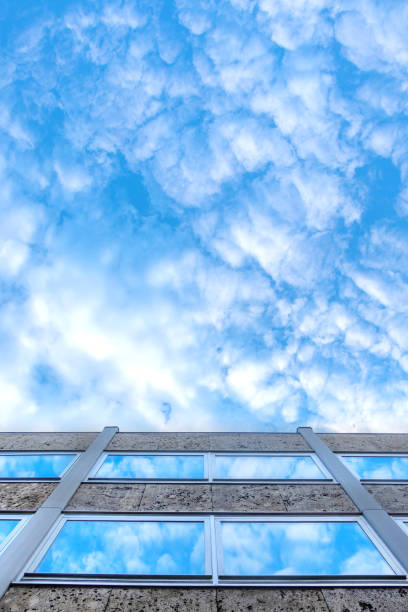 Close-up of a white residential building in a low angle view with glass railings in Miami, Florida. Building exterior with glass railings on its floating balconies.