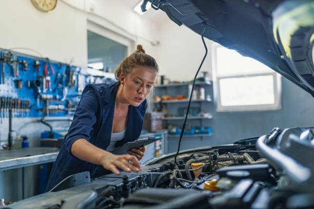 making some adjustments to her car - auto repair shop adult auto mechanic blue imagens e fotografias de stock